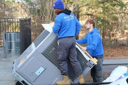 Two technicians unloading an HVAC unit.
