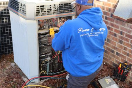 Technician working on HVAC wearing blue Powers and Gregory hoodie.