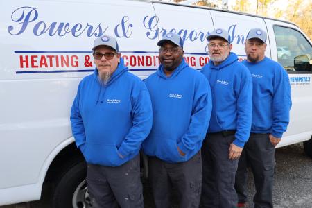 Four Powers and Gregory technicians wearing merch and standing in front of the company work van.